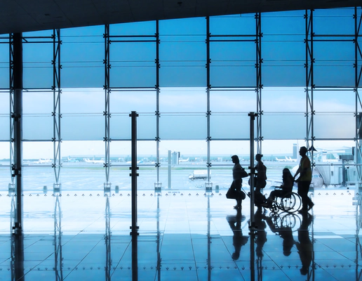 Four silhouettes of people in an airport setting, with a man and woman walking together with suitcases, followed by a wheelchair user being pushed by another person Four silhouettes of people in an airport setting, with a man and woman walking together with suitcases, followed by a wheelchair user being pushed by another person
